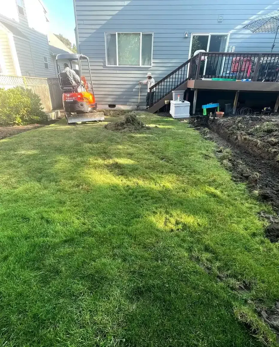 HD Landscape crew and mini excavator trenching a foundation drainage installation in a Portland backyard