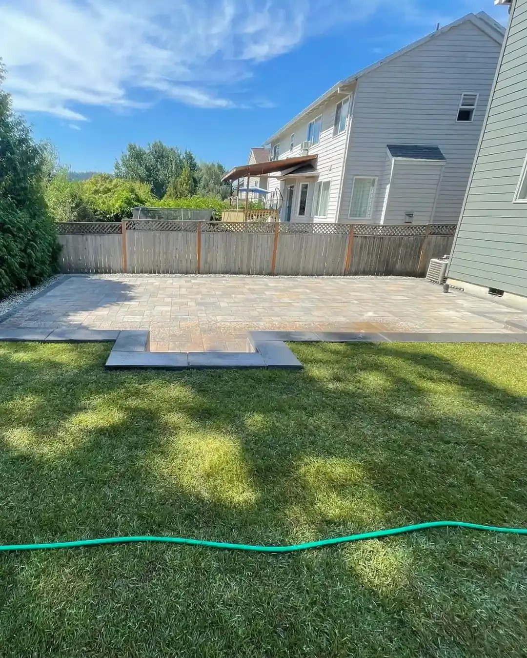 Completed paver patio with step-down landing and green backyard lawn installed by HD Landscape in Tualatin