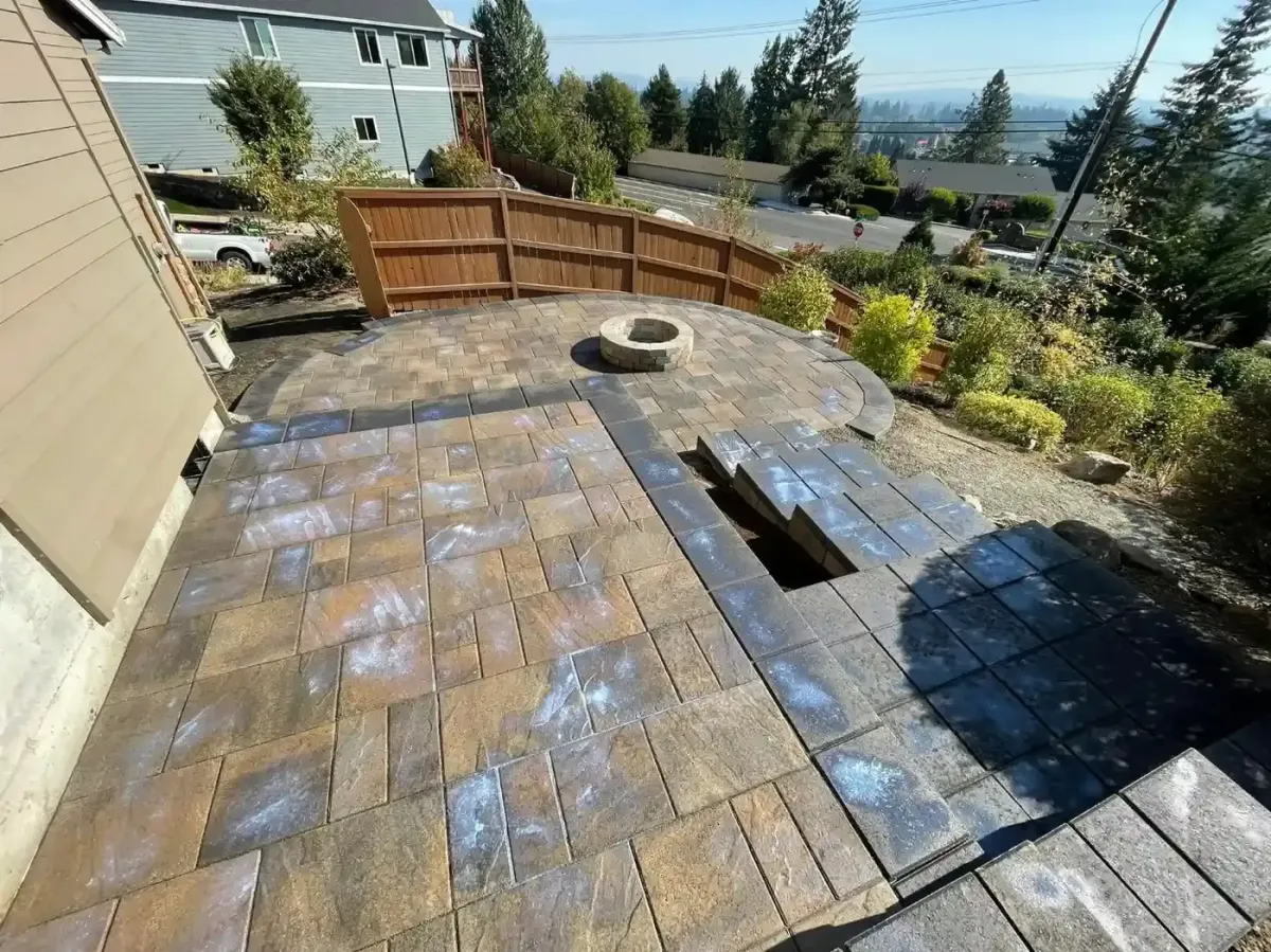 Aerial view of completed circular paver patio with stone fire pit ring, curved cedar fence, and hillside view by HD Landscape in West Linn