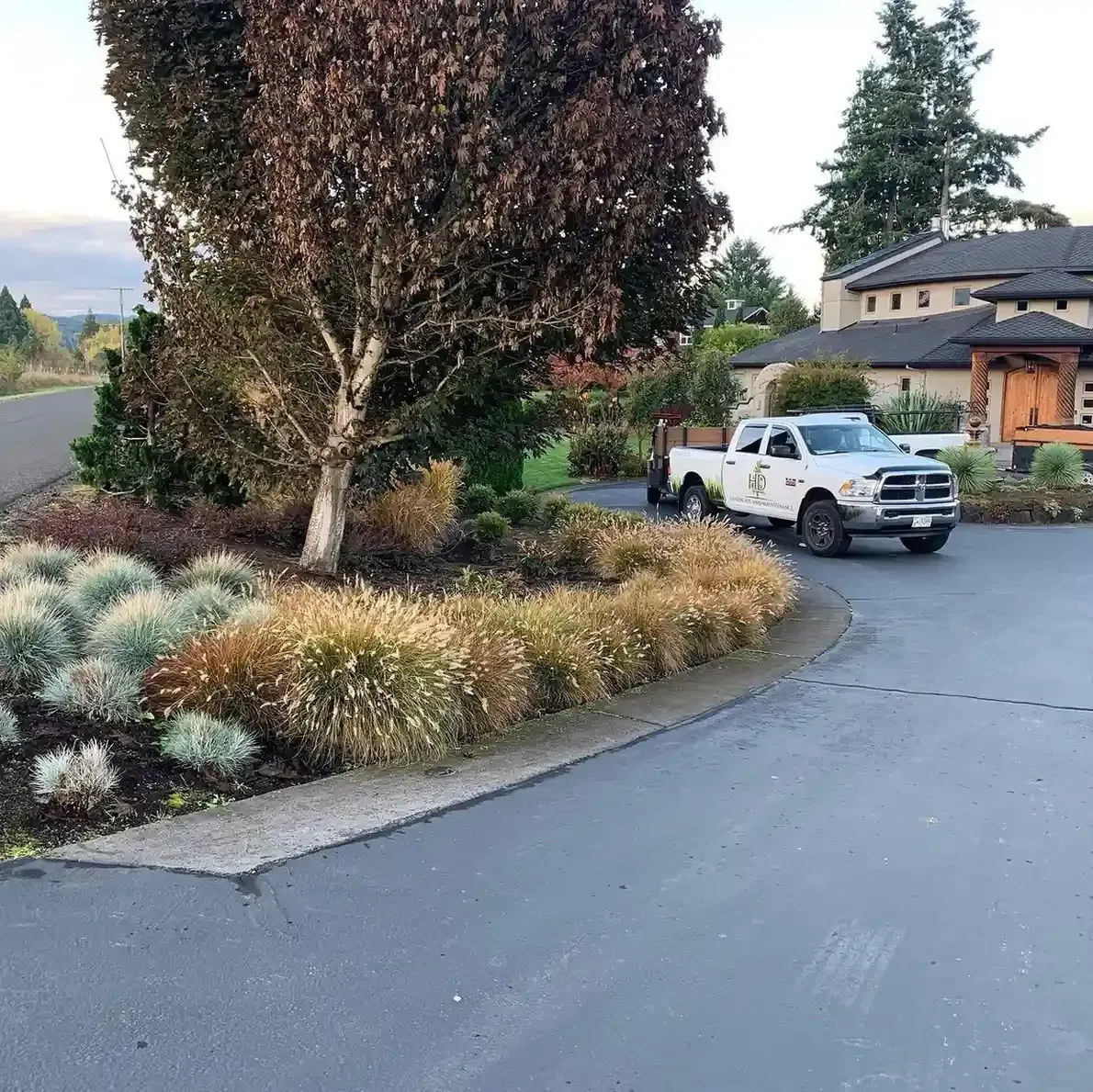 HD Landscape and Maintenance truck beside a manicured ornamental grass and shrub island at a Newberg residential property