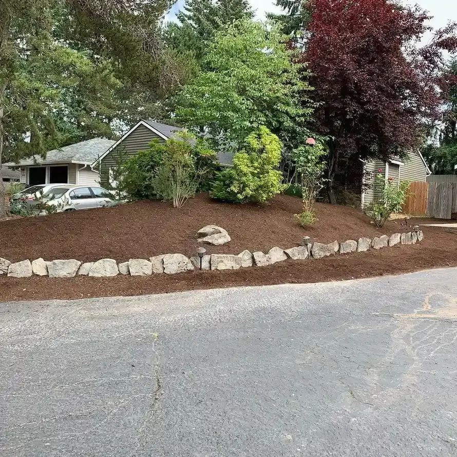Residential landscape installation with mulched planting bed, boulder edging, and path lights in Sherwood