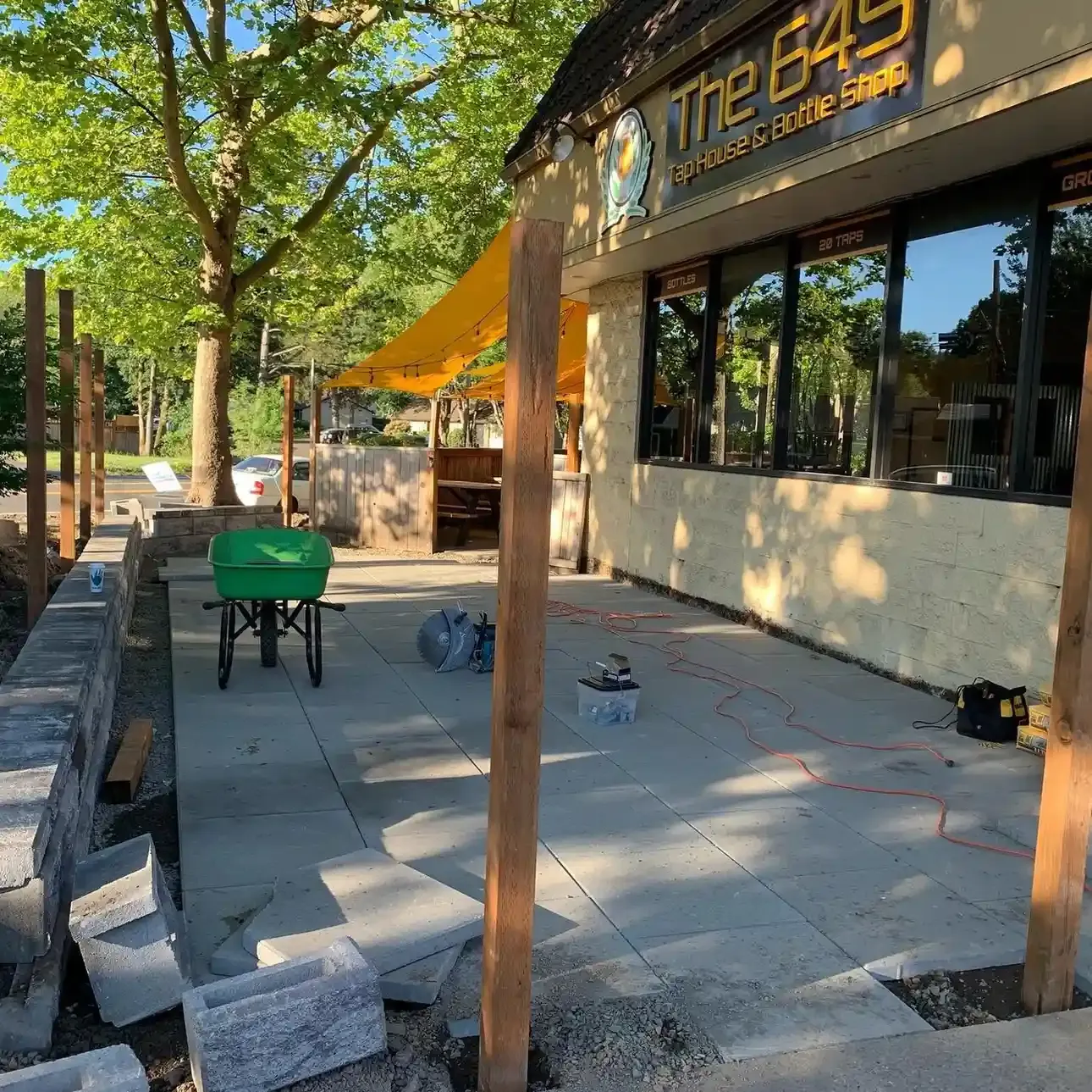 HD Landscape commercial hardscaping installation with concrete patio, pergola posts, and block wall at Portland area business