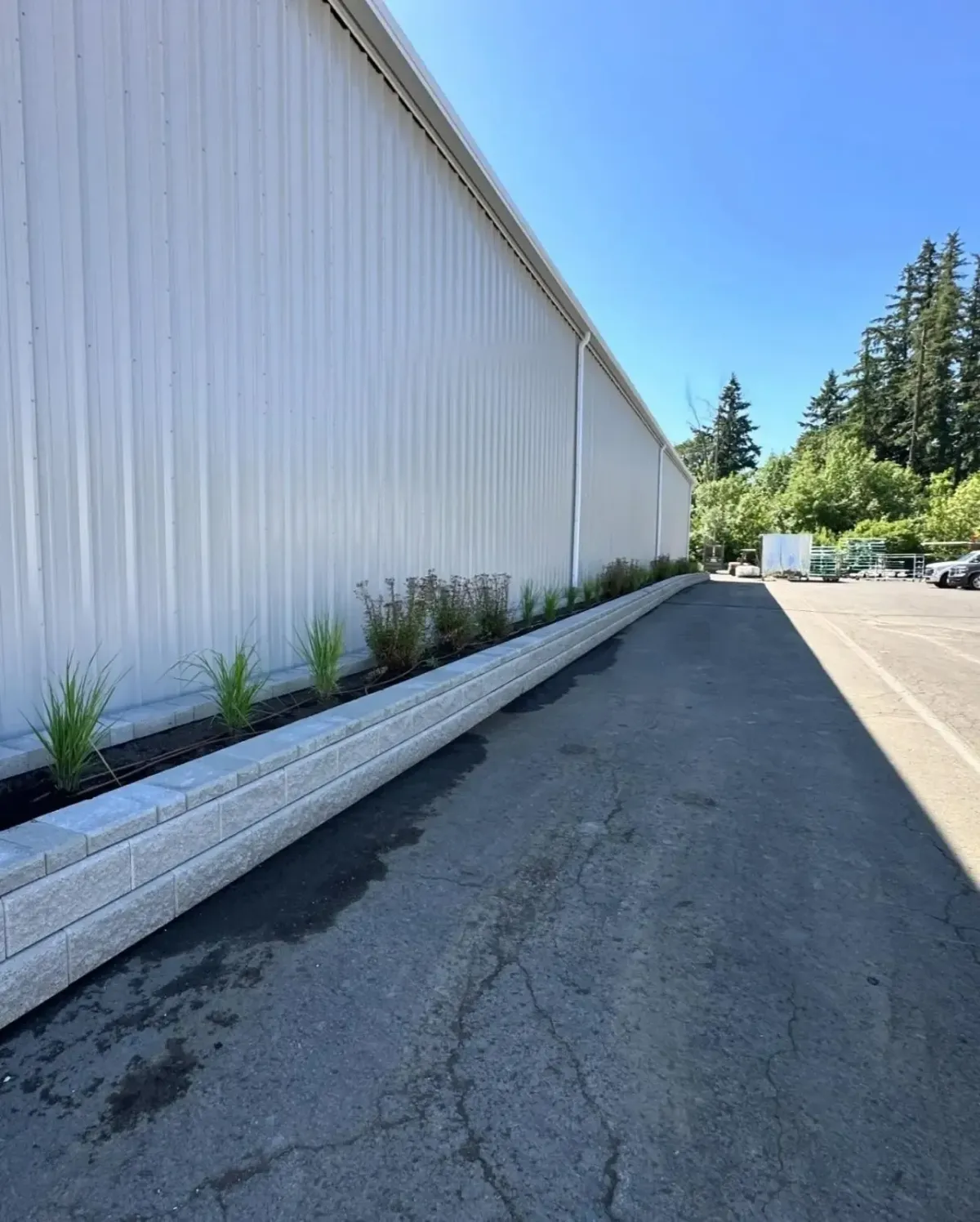 Commercial block planter wall with ornamental grass and shrub plantings along warehouse building by HD Landscape in Hillsboro