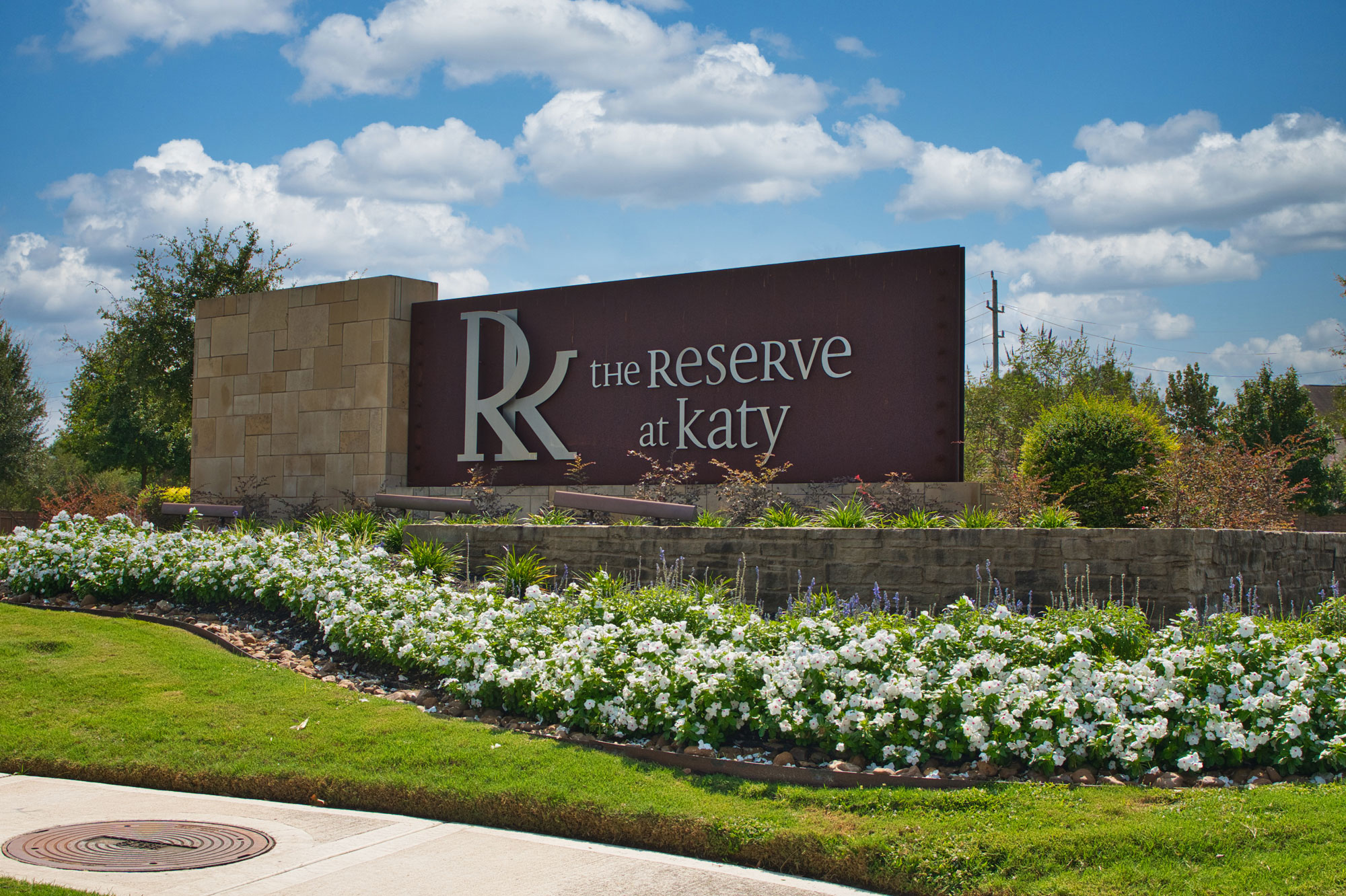 Landscaped community entrance with seasonal flower beds and manicured lawn in Katy, Texas
