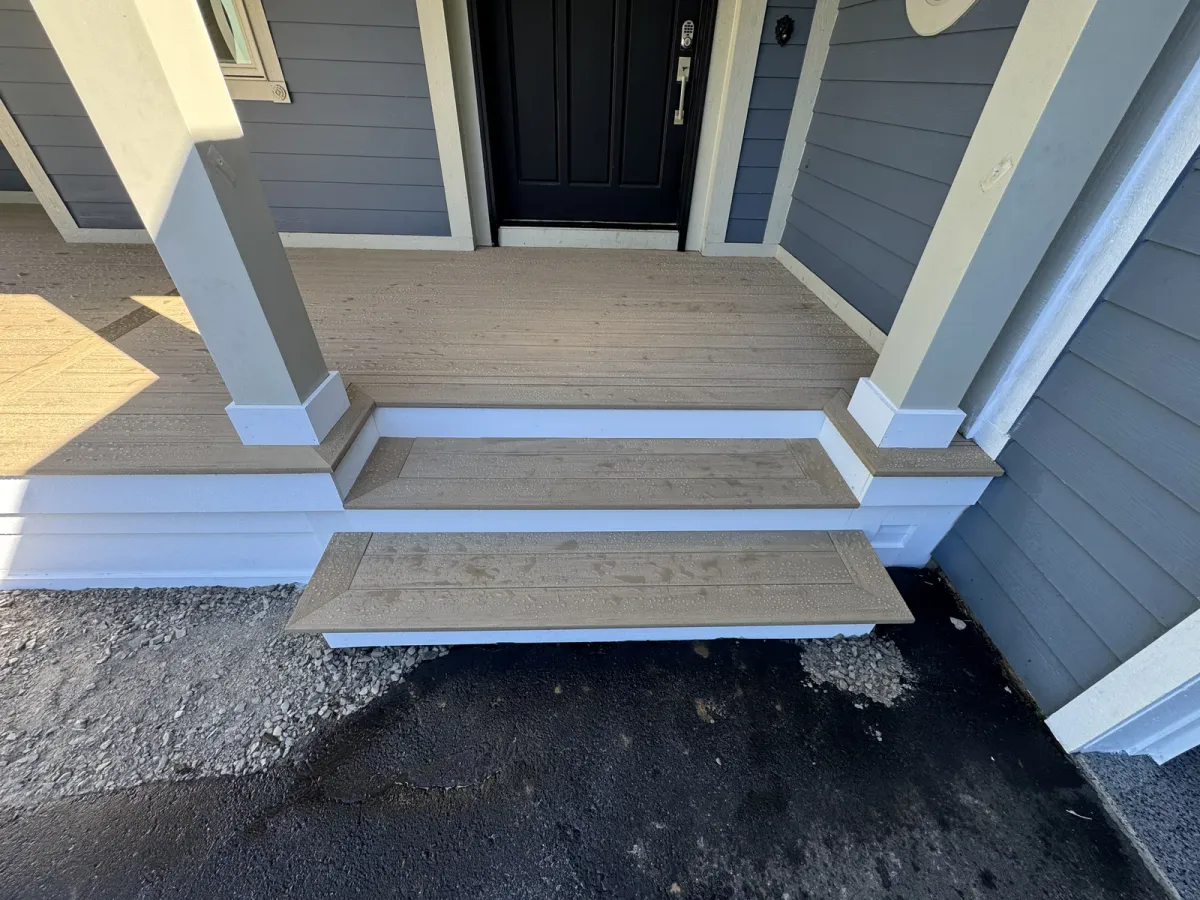 Wide finished porch steps beside a blue-sided home