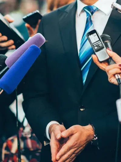 Man in a suit speaking to to reporters