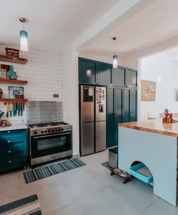 Teal industrial style kitchen with stainless steel stove, subway tile backsplash, and open wooden shelves.