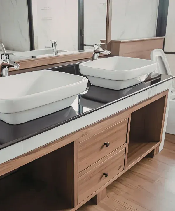 A modern bathroom featuring a walk-in shower with white geometric tiles, a white toilet, and a white vanity with black fixtures.