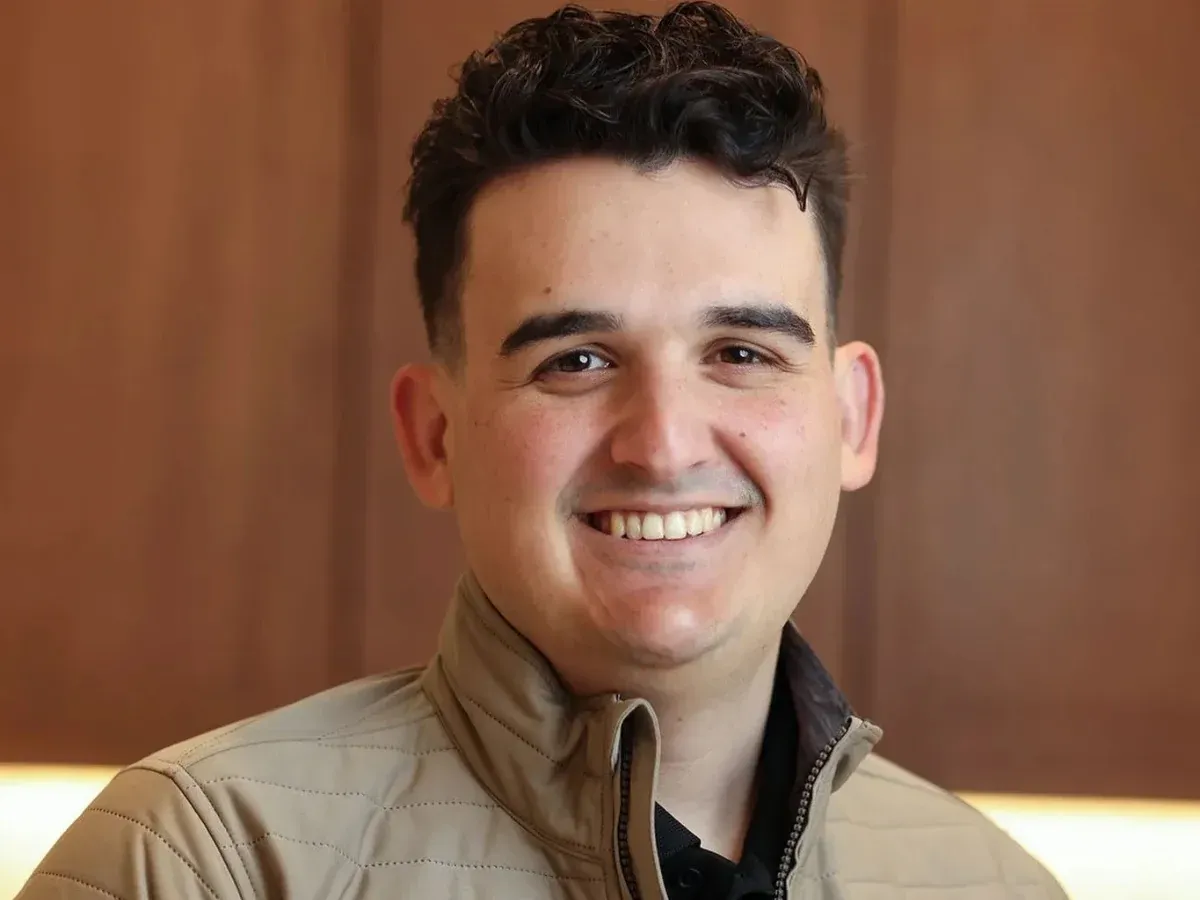 Smiling professional team member wearing a tan jacket