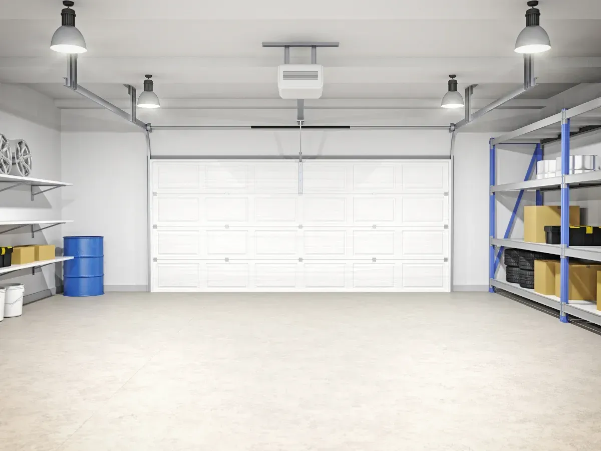 A clean, modern garage interior with a closed white panel garage door, shelving on both sides, and ceiling lights.