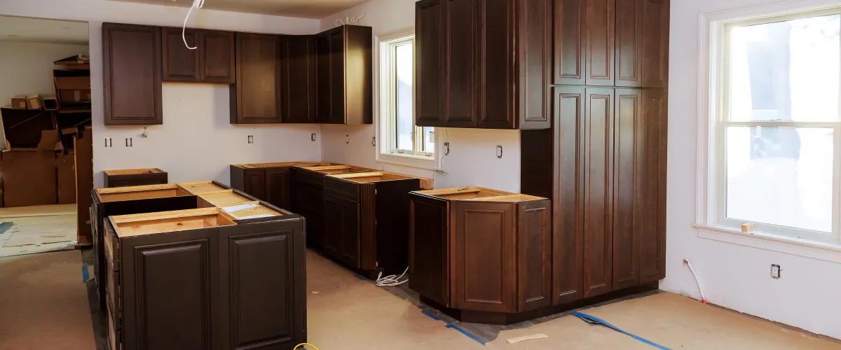 A newly installed white kitchen with base and wall cabinets, including a framed island, during home construction.