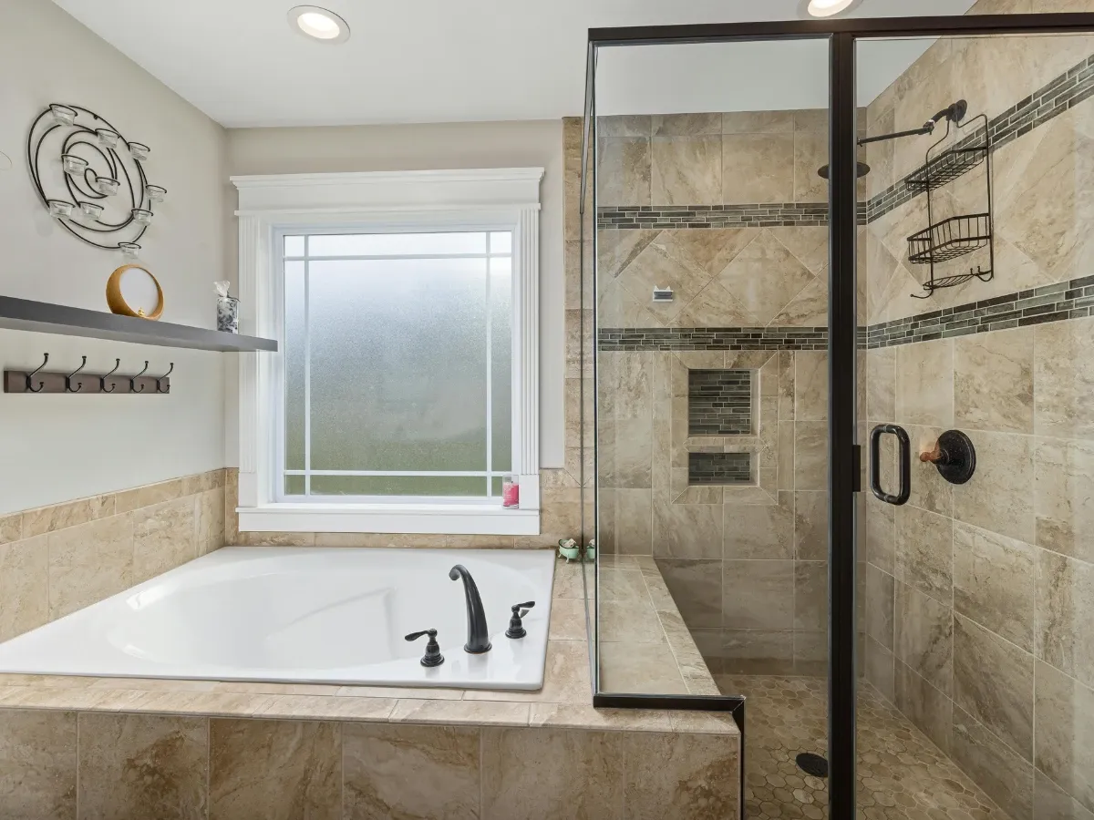 A luxurious walk-in shower with white and gray marble-patterned tiles, glass enclosure, and a built-in bench.