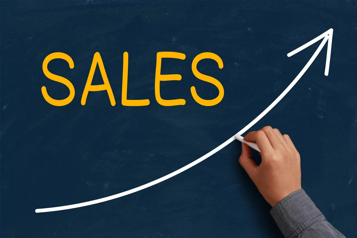 Hand drawing an upward sales arrow on a chalkboard, symbolizing growth and momentum in a sales process.