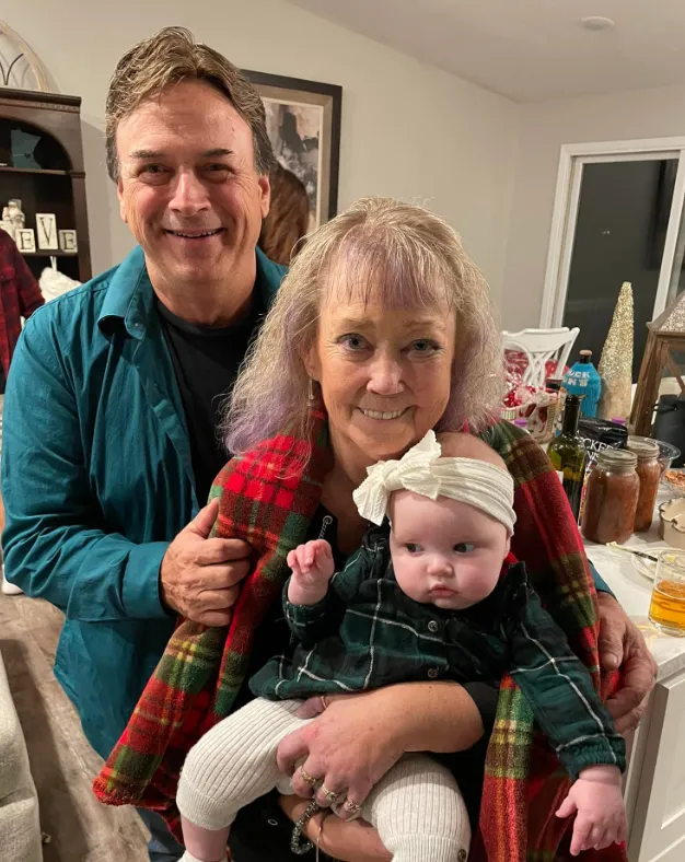 Grandparents holding their granddaughter during the holidays