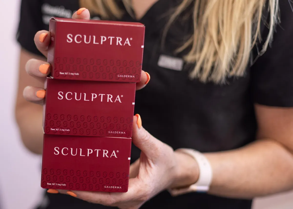 Sculptra, a collagen biostimulator used for injections at 29 Aesthetics to treat lines and wrinkles. Photo is of Amy, provider, holding several containers of Sculptra in her home-office and spa