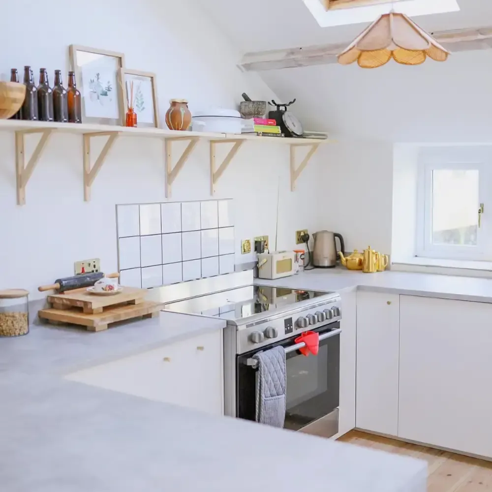 Scandinavian loft kitchen with skylights, exposed beams, natural wood open shelving, white subway tiles, and woven pendant light by Blueprint Kitchens