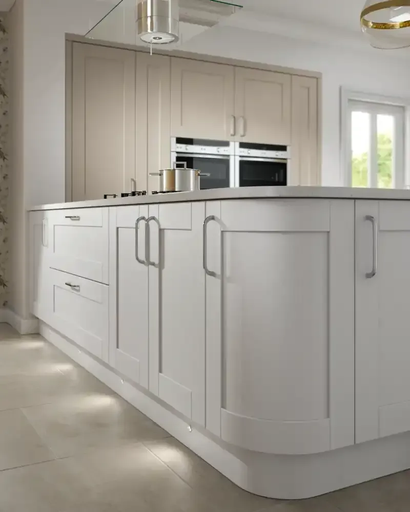 Modern bespoke kitchen design featuring cream painted cabinets with traditional Shaker-style door panels, integrated appliances, curved kitchen island with breakfast bar seating, and under-cabinet LED lighting - Blueprint Kitchens Cornwall