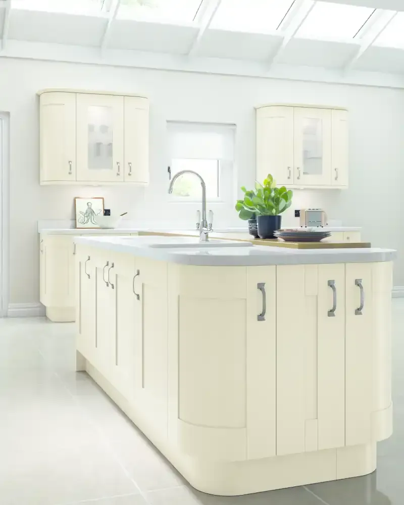 Contemporary bespoke kitchen with grey painted Shaker cabinets, white quartz worktops, copper pendant lights over central island, integrated range cooker, and open shelving storage - Blueprint Kitchens Cornwall