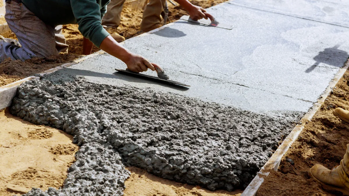 Worker leveling a freshly poured concrete patio slab inside wood forms in Aurora, CO
