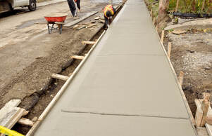Fresh concrete sidewalk installation with control joints being finished in Aurora, CO