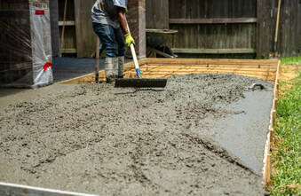 Finisher hand troweling a freshly poured concrete slab for a smooth surface in Aurora, CO