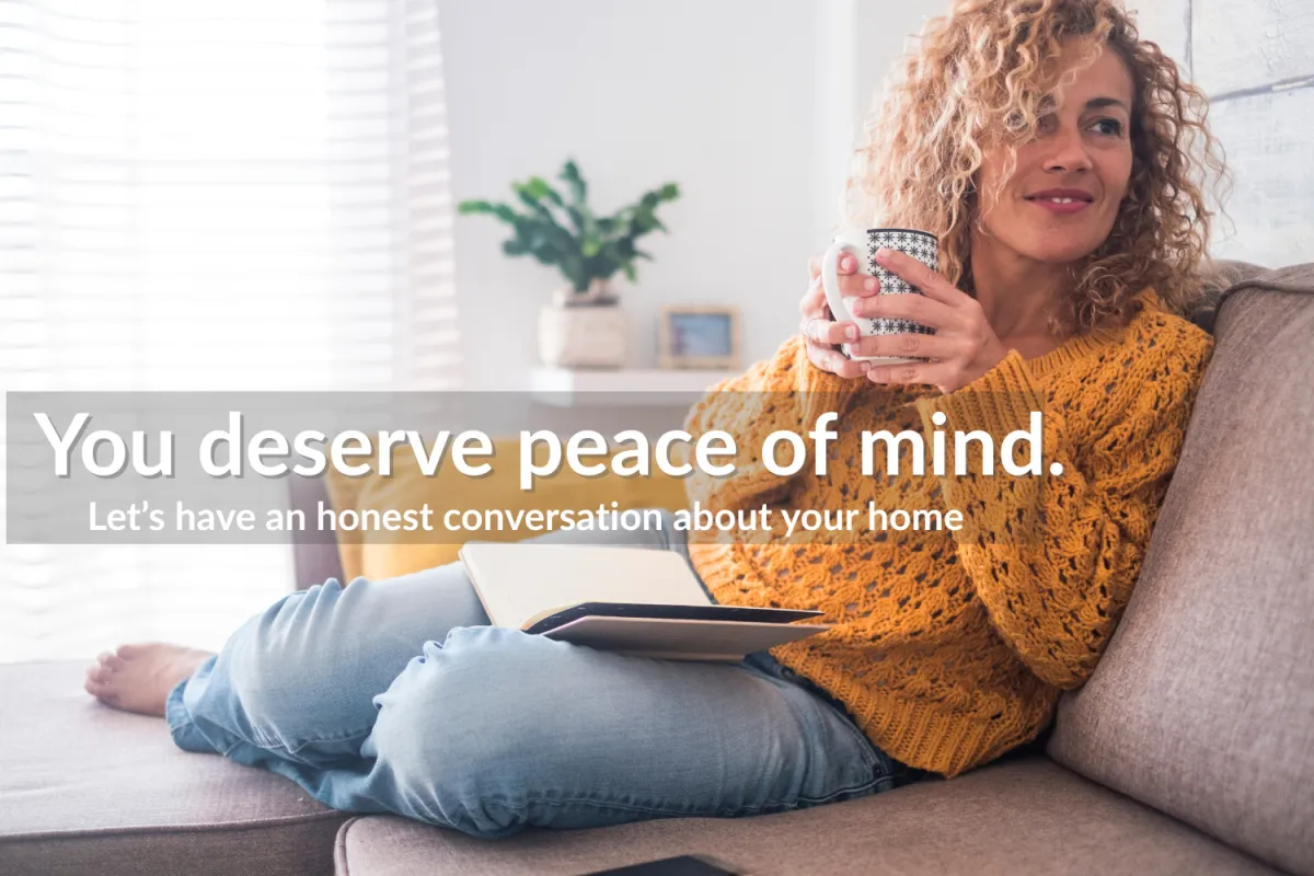 Woman relaxing on a couch with a coffee mug and tablet, smiling peacefully in a cozy living room setting.