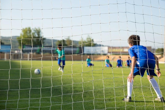 Children playing sport outdoors, highlighting the importance of free play and long-term youth athlete development