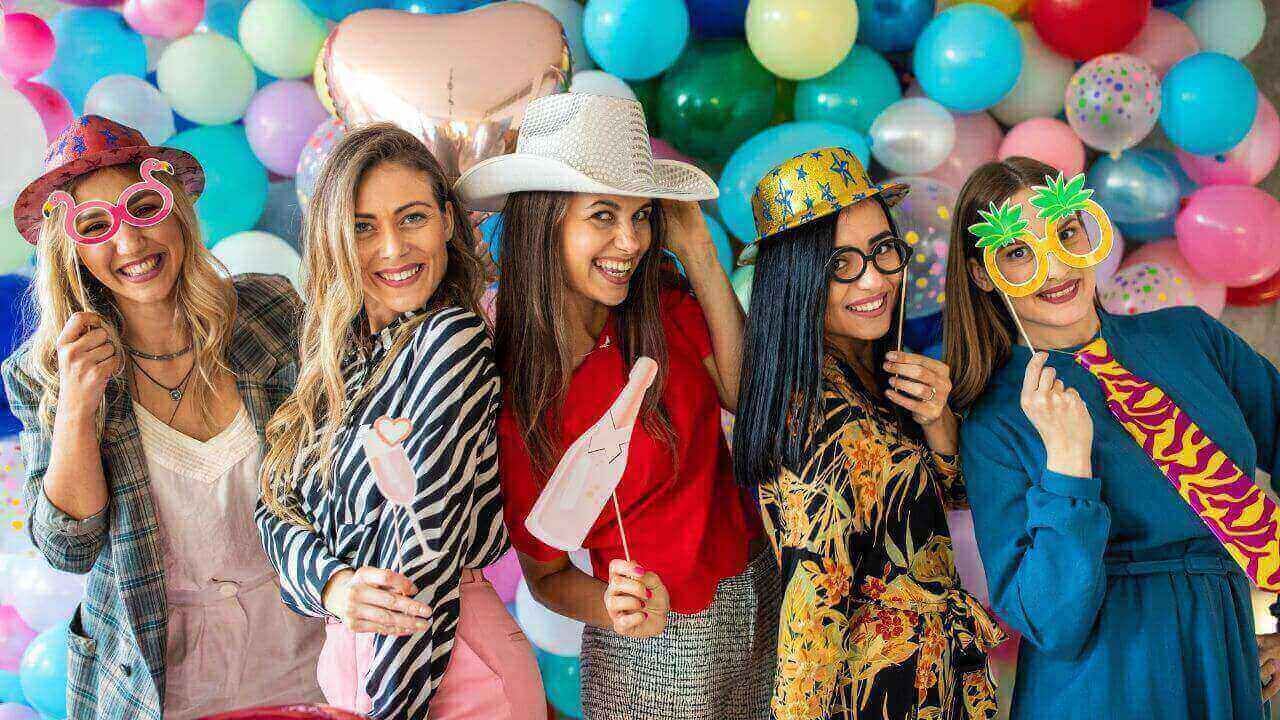 A group of women are posing for a picture in front of a wall of balloons.