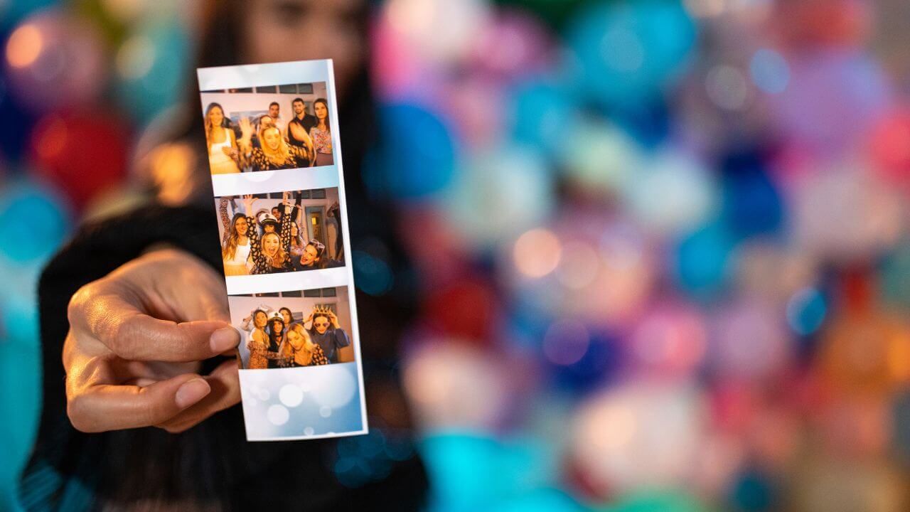 A woman is holding a polaroid picture of a group of people.