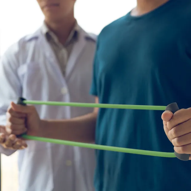 Patient using resistance band under Plano chiropractor guidance