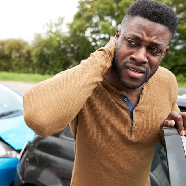 Man rubbing neck whiplash after car accident injury