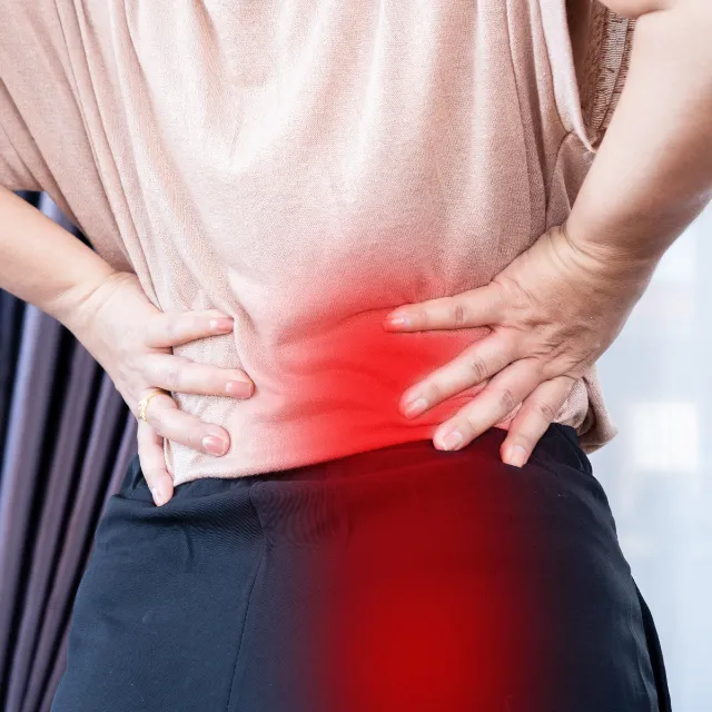 Patient holding lower back depicting sciatica pain and numbness treatment by Plano chiropractor