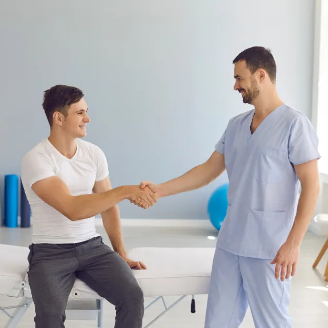 Plano chiropractor shaking hands with a patient in treatment room