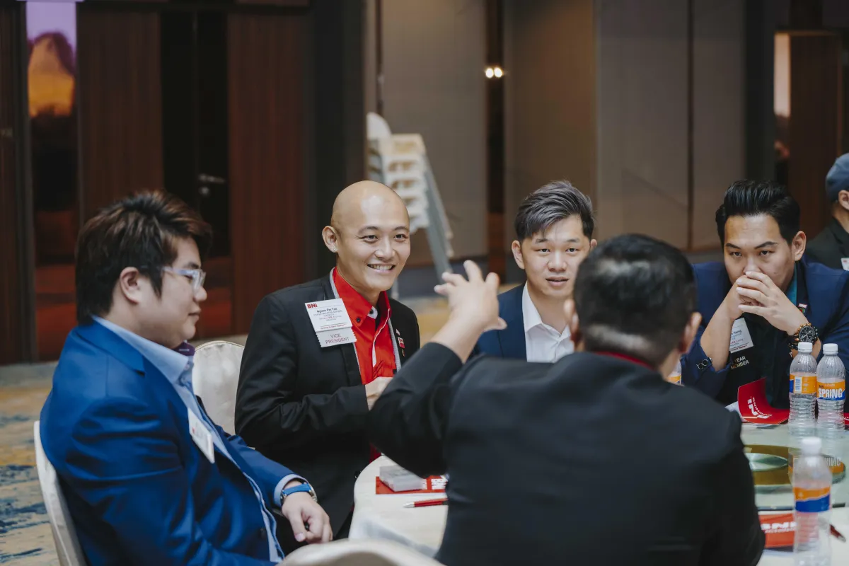 four people watching on white MacBook on top of glass-top table