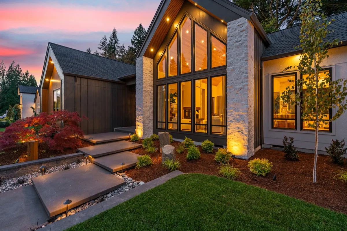 Luxury modern home exterior at dusk with warm interior lighting