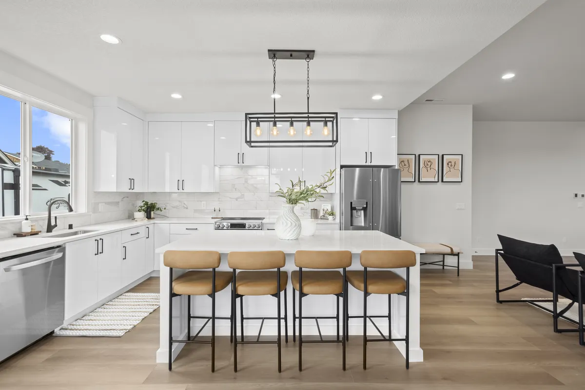 White kitchen with island, stools, and pendant lighting