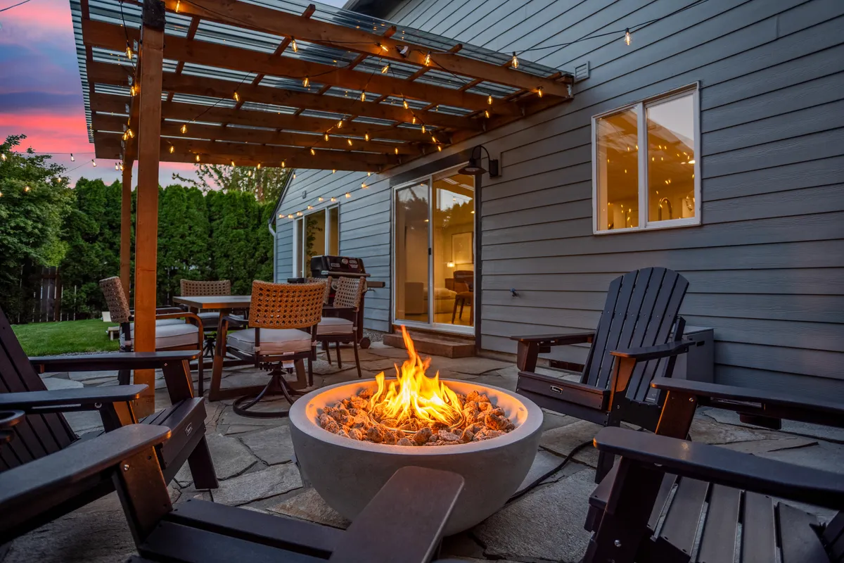 Outdoor patio with pergola and glowing fire pit at twilight