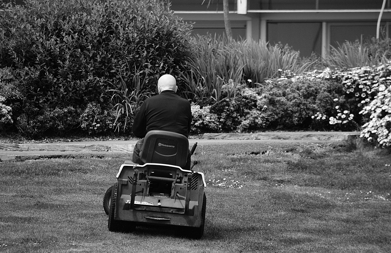 black and white photo of a man on a ride on mower