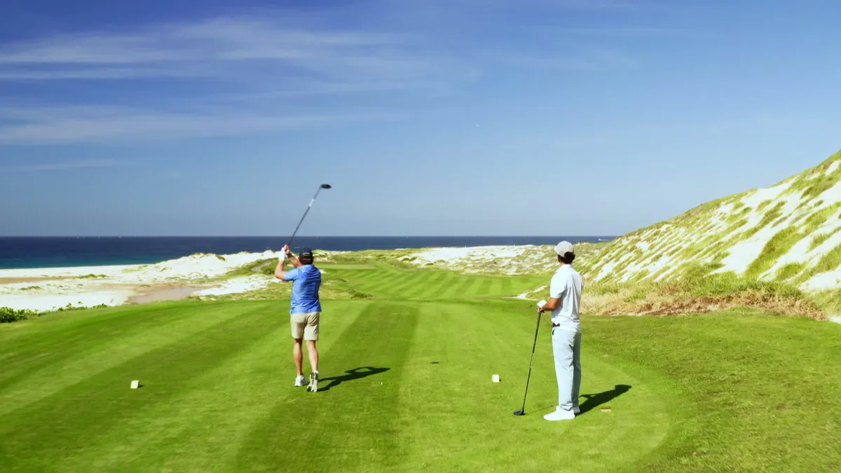 Two golfers on an oceanfront tee box