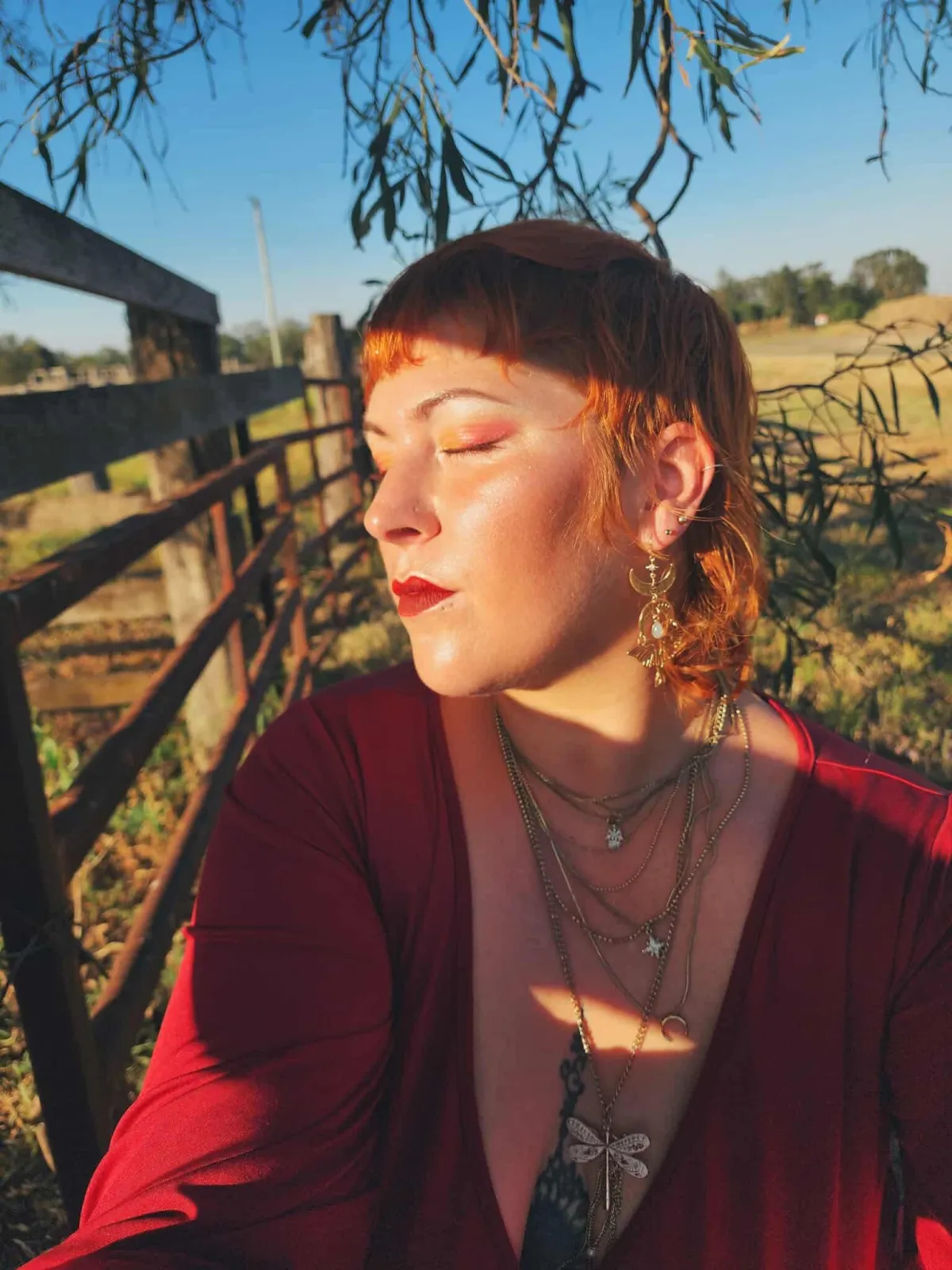 beautiful red haired woman sitting under a tree in both light and shadow
