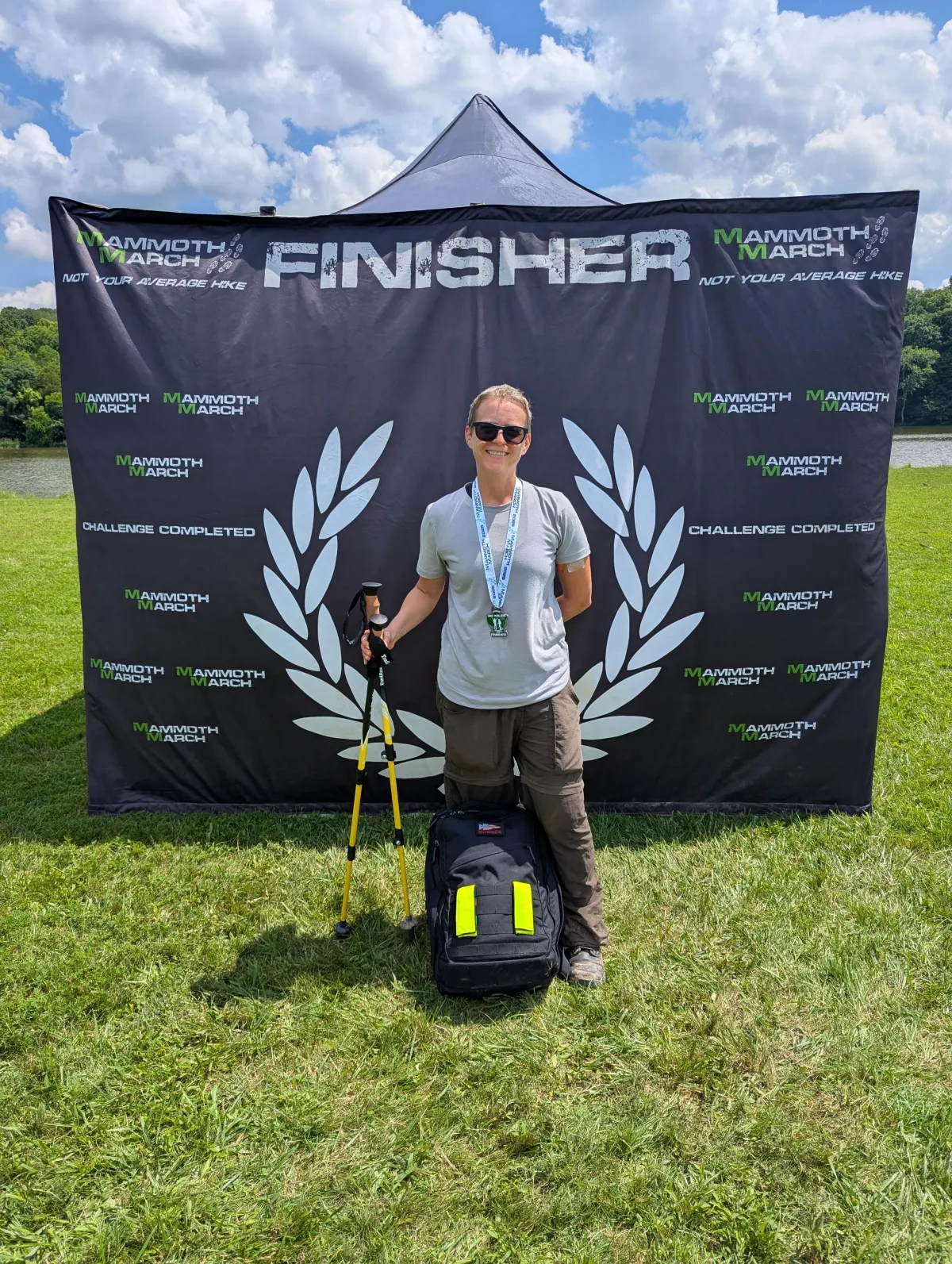 Dr. Jeanette posing with her rucksack at the Finisher area after completing a Mammoth March endurance event, representing her experience as a runner and rucker.