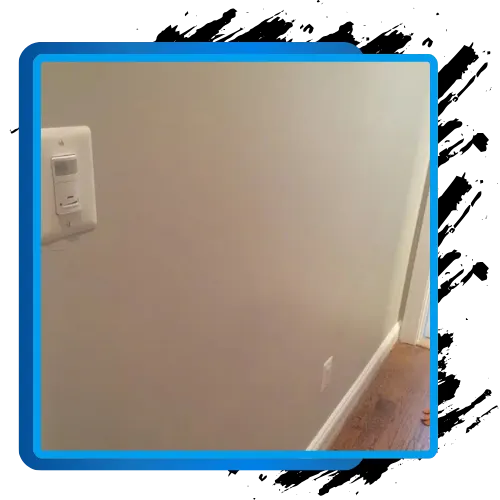 Repaired wall with electrical outlet and trim illustrating drywall repair services.