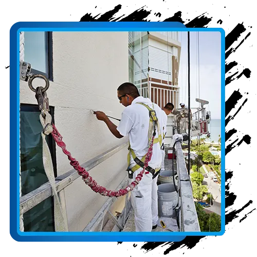 Commercial painter working on exterior building facade with safety harness