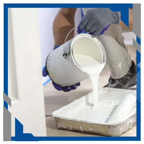 Painter pouring paint into tray for interior painting project.