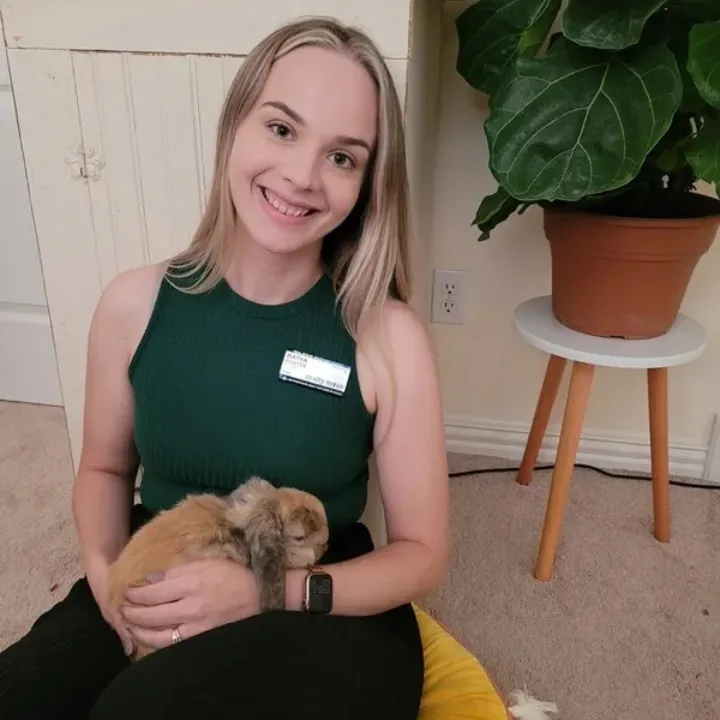 Batya Porter, a dedicated real estate professional, smiling while holding a bunny in a cozy home setting