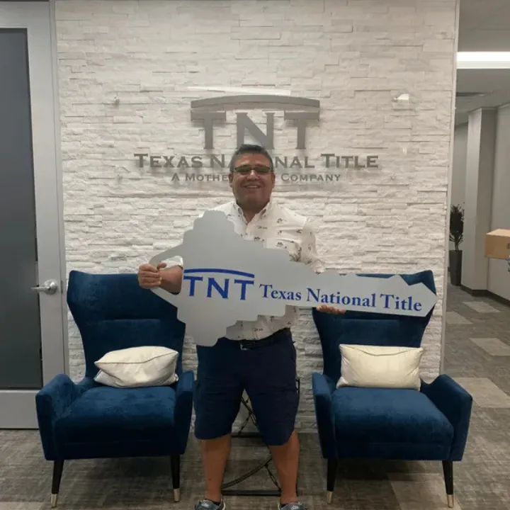 A proud new homeowner celebrating their successful closing at Texas National Title with a custom key sign.