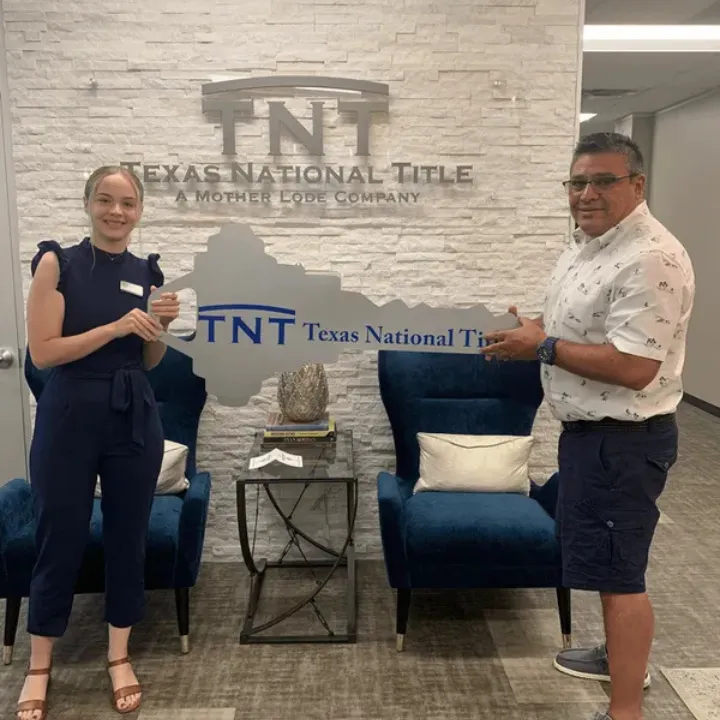 Batya Porter handing keys to a happy client at Texas National Title after a successful real estate closing.