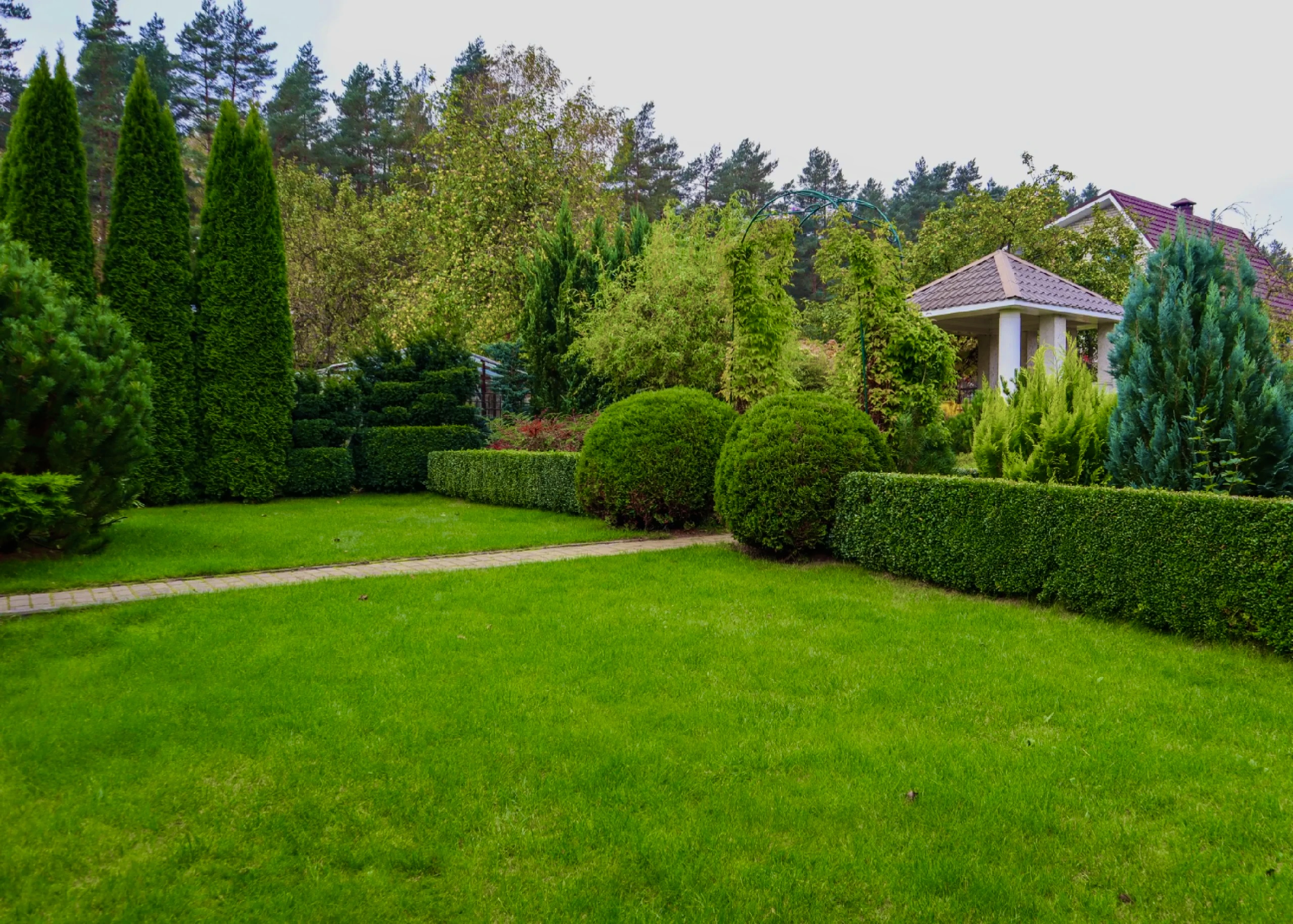 Parkosított családi ház kertje rendszeres kertkarbantartással és sövényvágással