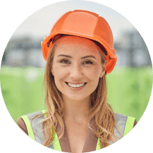 Smiling female construction worker in an orange hard hat and reflective safety vest.