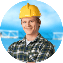 Smiling male construction worker in a plaid shirt and yellow hard hat with blue sky background.